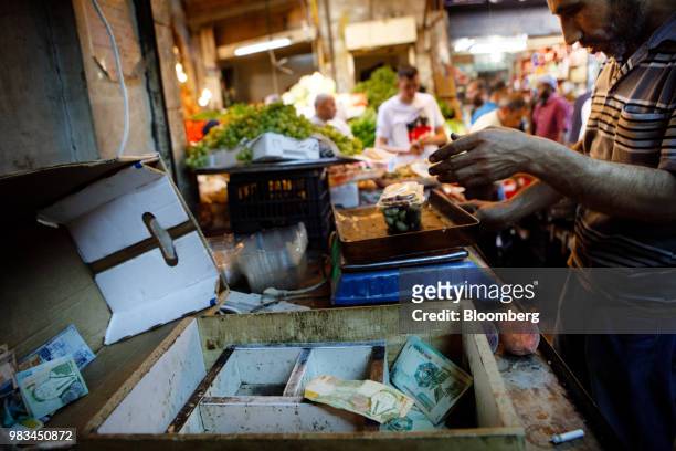 Market trader weighs plums beside a tray full of Jordanian dinar banknotes at a local fruit and vegetable market in Amman, Jordan, on Thursday, June...