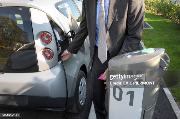 An Autolib official checks the renting system machine near a Bluecar at the Autolib operational Center in Vaucresson, near Paris, on September 30...