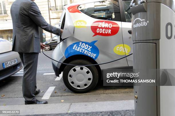 An Autolib official checks the electric plug system of a Bluecar on October 2, 2011 in Paris, at the first day of a test session of the Autolib...