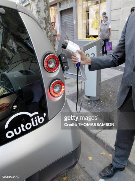 An Autolib official checks the electric plug system of a Bluecar on October 2, 2011 in Paris, at the first day of a test session of the Autolib...