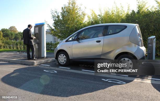 An Autolib official checks the renting system machine near a Bluecar at the Autolib operational Center in Vaucresson, near Paris, on September 30...