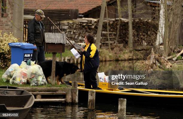 Jutta Pudenz, an employee of German postal carrier Deutsche Post DHL, delivers mail to a local resident from her falt-bottomed canoe in the narrow...