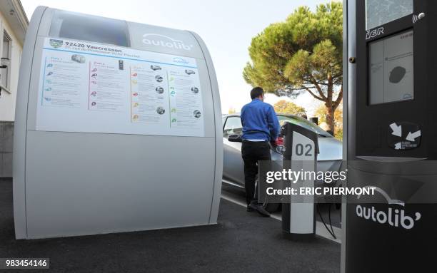 An Autolib official checks the renting system machine near a Bluecar at the Autolib operational Center in Vaucresson, near Paris, on September 30...