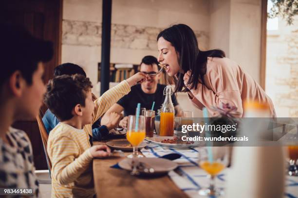 lille son ger mor pannkaka under frukost med familj - children eating breakfast bildbanksfoton och bilder