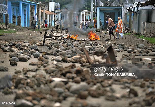 Man stokes a fire on a street barricaded with boulders and burning tyres and burning tires at Moheli , in the Indian Ocean Archipelago of Comoros, on...