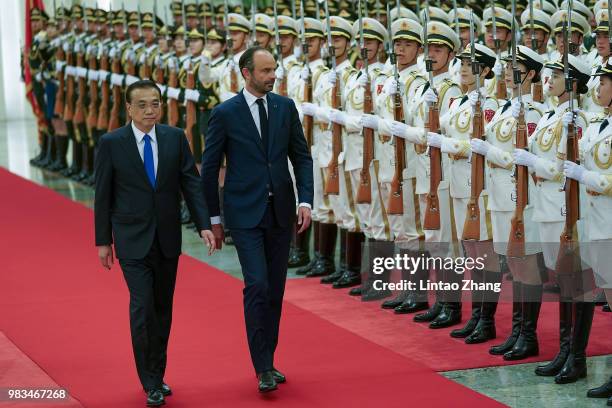 Chinese Premier Li Keqiang accompanies French Prime Minister Edouard Philippe as they review an honour guard during a welcoming ceremony inside the...