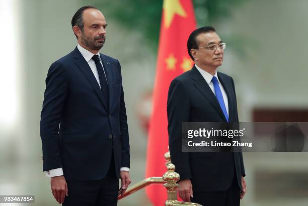 Chinese Premier Li Keqiang and French Prime Minister Edouard Philippe listen to their national anthems during a welcoming ceremony inside the Great...