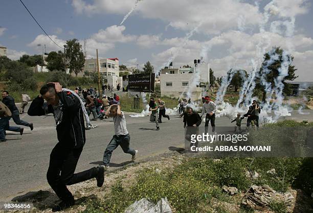 Protesters run for cover as Israeli troops fire tear gas to disperse the crowd during a demonstration in Nabi Saleh in the Ramallah district against...