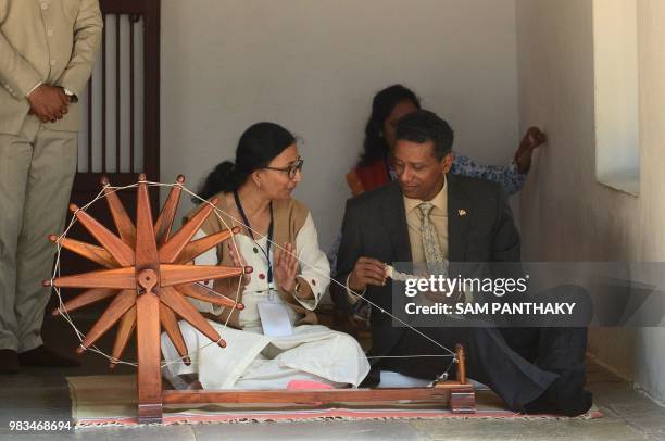 Seychelles President Danny Faure takes lessons on a spinning wheel during his visit to the Gandhi Ashram, where Indian independence icon Mahatma...