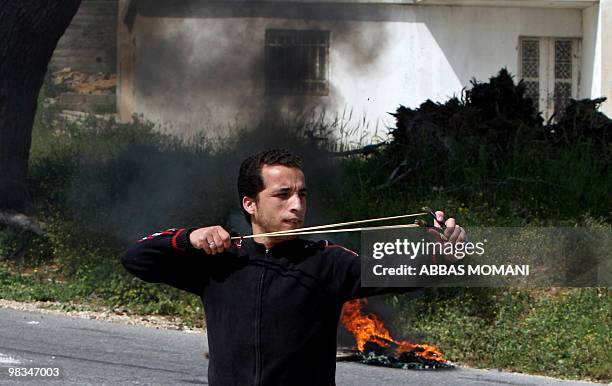 Palestinian protester uses a slingshot to throw stones at Israeli troops during a demonstration in Nabi Saleh in the Ramallah district against the...