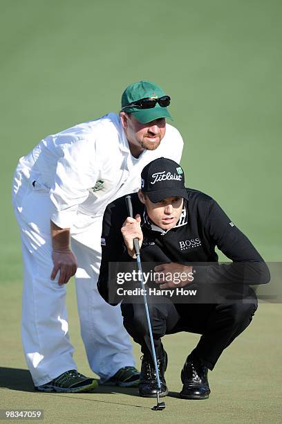 Nick Watney lines up a putt with the help of his caddie Tim Goodell on the second hole during the second round of the 2010 Masters Tournament at...