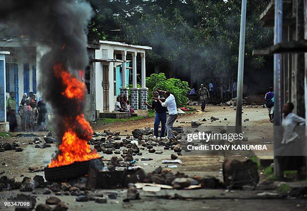 Two demonstrators jostle with each other on a street barricaded with boulders and burning tires at Moheli in the Indian Ocean Archipelago of Comoros...