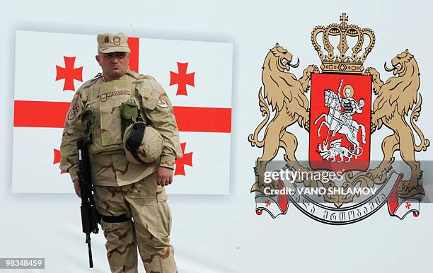Soldier from the 31st battalion of Georgian Armed Forces stands in front of a drawing of a Georgian flag and National Emblem during a farewell...
