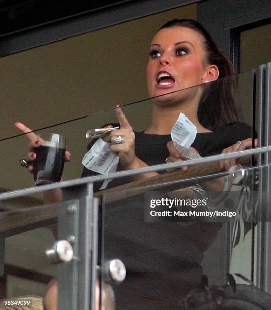 Coleen Rooney pulls a face whilst holding her betting slips and rolled up ten pound notes as she watches the racing on 'Ladies Day' of the John...