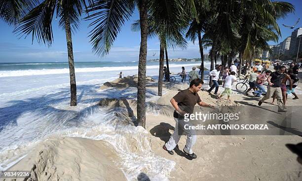 People run away from the waves flooding Rio de Janeiro's Copacabana beach and its sidewalk on April 9, 2010. The unusual roughness seen these days in...
