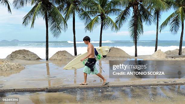 Surfer walks along the flooded sidewalk of Rio de Janeiro's Copacabana beach on April 9, 2010. The unusual roughness seen these days in Guanabara Bay...