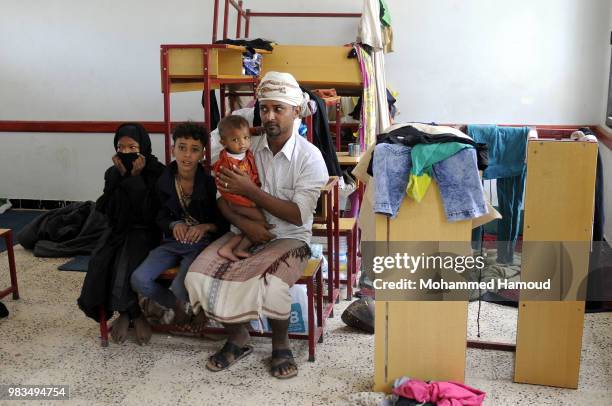 Displaced father who fled the war in Yemen’s port city of Hodeida with his children sits inside a class organized for them to stay in as a shelter on...