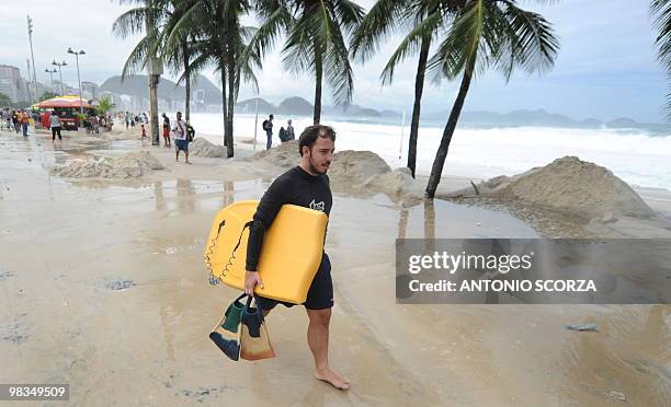 Bodysurfer walks along the flooded sidewalk of Rio de Janeiro's Copacabana beach on April 9, 2010. The unusual roughness seen these days in Guanabara...