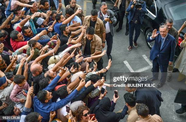 Turkey's President Recep Tayyip Erdogan, leader of the Justice and Development Party is greeted by supporters as he and his wife leave the polling...