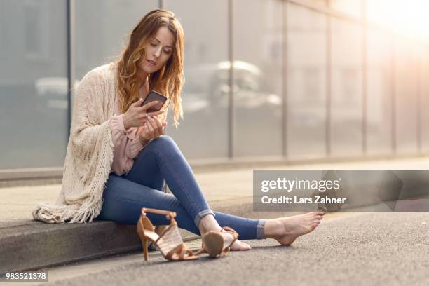 attractive woman sitting on the kerb of a street - kerb fotografías e imágenes de stock