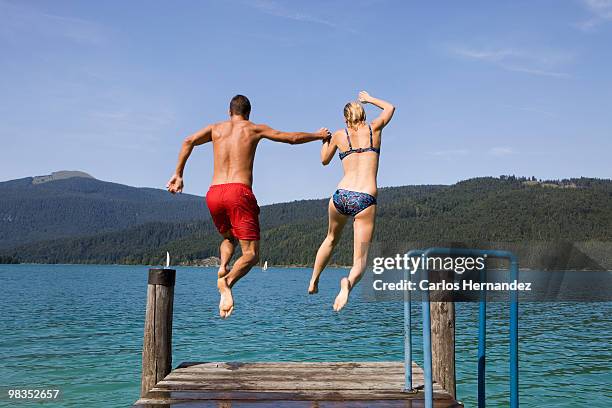 a couple jumping into the water - just do it fotografías e imágenes de stock