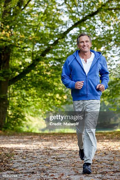 middle aged man jogging - un solo hombre maduro and sonrisa fotografías e imágenes de stock