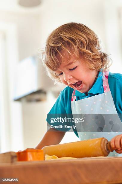 young boy rolling dough with rolling pin - rolling pin photos et images de collection