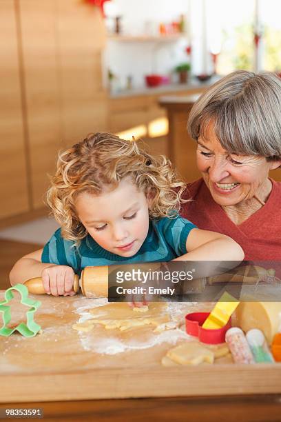 grandchild and grandma making biscuits - woman front and back stock-fotos und bilder