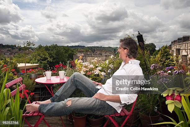 man sitting on balcony - té terraza fotografías e imágenes de stock
