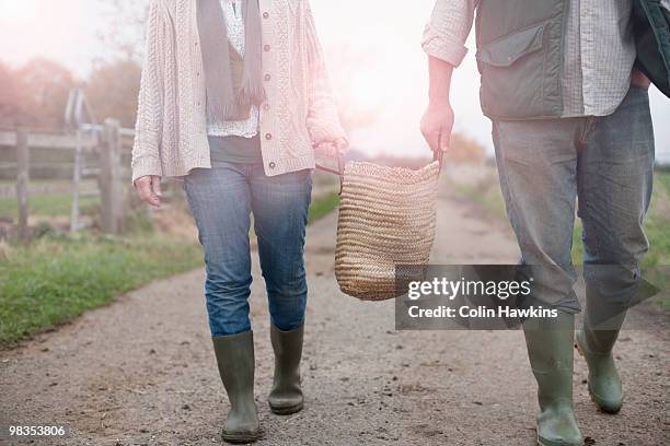 couple carrying basket in countryside - wellington boots stock pictures, royalty-free photos & images