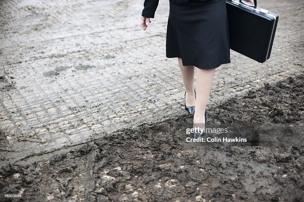 Business woman walking in muddy farm
