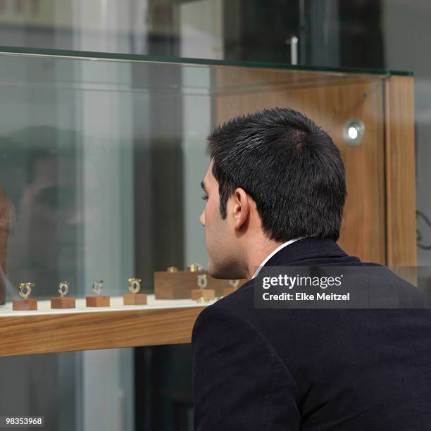 man looking at jewelry in shop window - jewellery store stock pictures, royalty-free photos & images