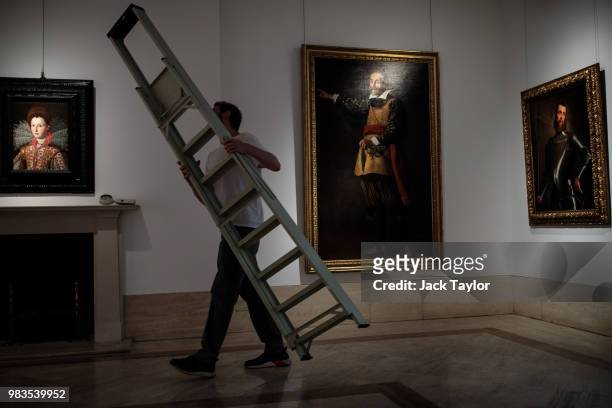 Gallery worker carries a ladder past 'Portrait of Francesca Gambereschi Baldovinetti' by Santi Di Tito, 'Portrait of the actor Francesco Andreini' by...
