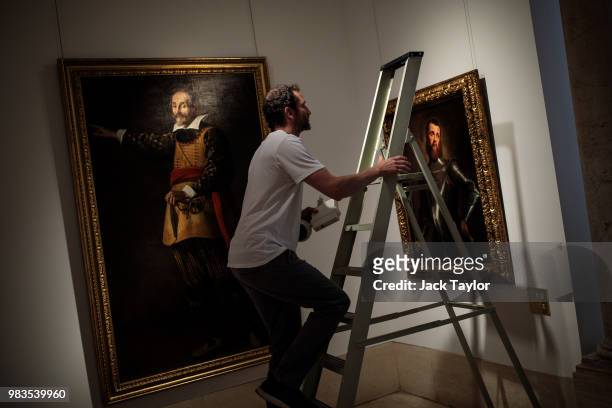 Gallery worker climbs a ladder to change a light in front of 'Portrait of the actor Francesco Andreini' by Valore Casini and 'Portrait of a military...