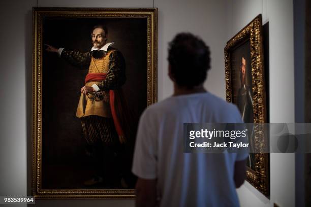 Gallery worker looks at 'Portrait of the actor Francesco Andreini' by Valore Casini and 'Portrait of a military commander, three-quarter length, in...