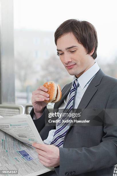 businessman reading whilst eating - man holding a burger stock pictures, royalty-free photos & images