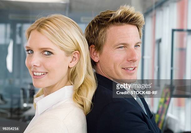 businessman and businesswoman in office standing back to back - rf business stock-fotos und bilder