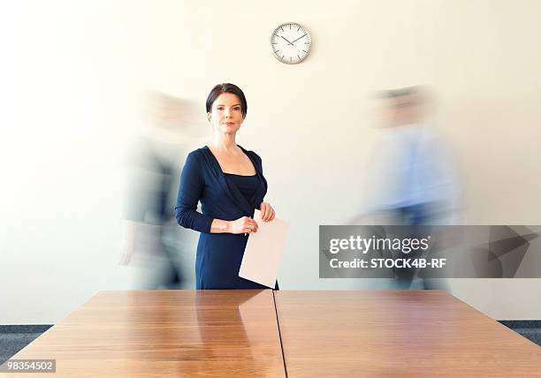 businesswoman in conference room with people in background passing by - portrait blurred background stockfoto's en -beelden