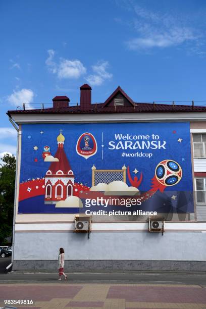June 2018, Russia, Saransk: Soccer, World Cup: A woman walking by a sign with the text "Welcome to Saransk". Photo: Andreas Gebert/dpa