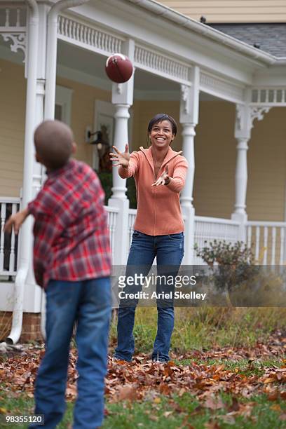 black mother and son throwing football - football season stock pictures, royalty-free photos & images