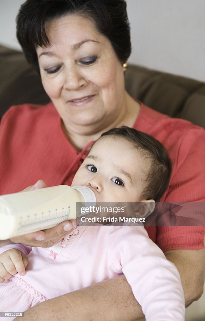Hispanic grandmother feeding baby