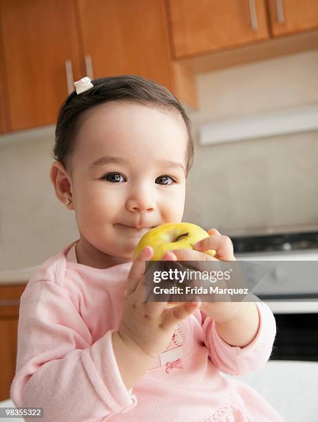 hispanic baby girl eating apple - cute mexican girl stockfoto's en -beelden