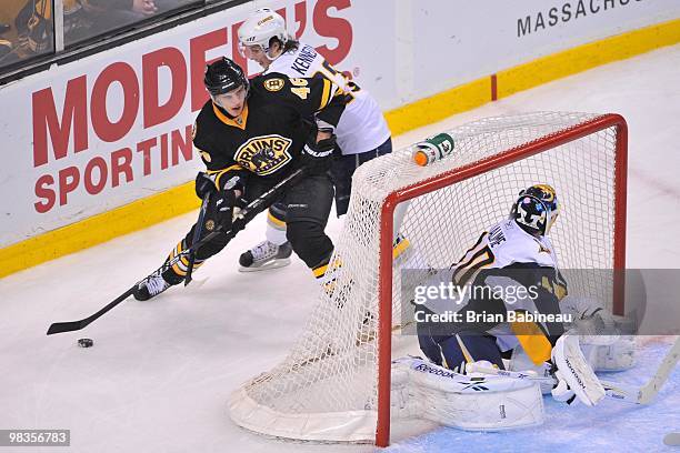 David Krejci of the Boston Bruins skates with the puck behind the net against Tim Kennedy and Patrick Lalime of the Buffalo Sabres at the TD Garden...