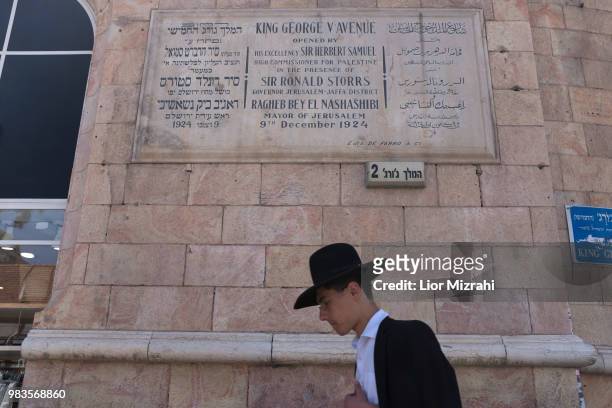 An Ultra Orthodox Jewish man walks under a dedication plaque in honor of King George V, in King George street in downtown on June 25, 2018 in...