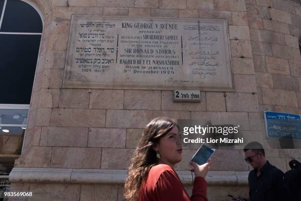 An Israeli woman walks under a dedication plaque in honor of King George V, in King George street in downtown on June 25, 2018 in Jerusalem, Israel....