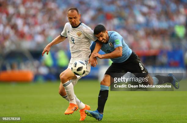 Luis Suarez of Uruguay challenge for the ball with Sergey Ignashevich of Russia during the 2018 FIFA World Cup Russia group A match between Uruguay...