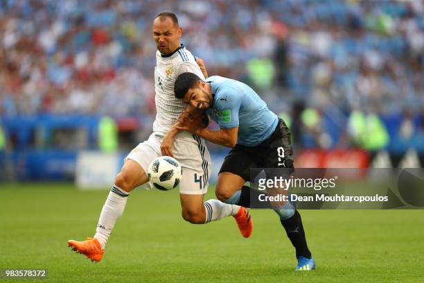 Luis Suarez of Uruguay challenge for the ball with Sergey Ignashevich of Russia during the 2018 FIFA World Cup Russia group A match between Uruguay...