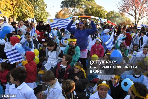 Schoolchildren and other people celebrate after Uruguay's striker Luis Suarez scored a free kick against Russia during World Cup match, as they watch...