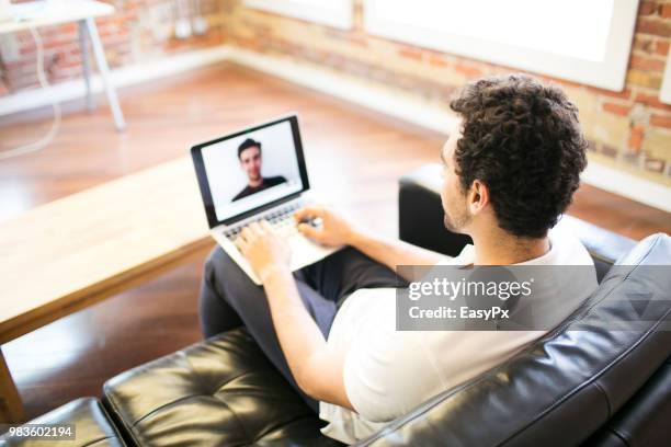 colleagues video conferencing with a laptop - presents easy a stockfoto's en -beelden