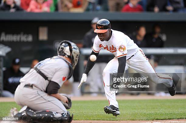 Felix Pie of the Baltimore Orioles slides safely into home plate in the eighth inning ahead of the tag of John Buck of the Toronto Blue Jays on...